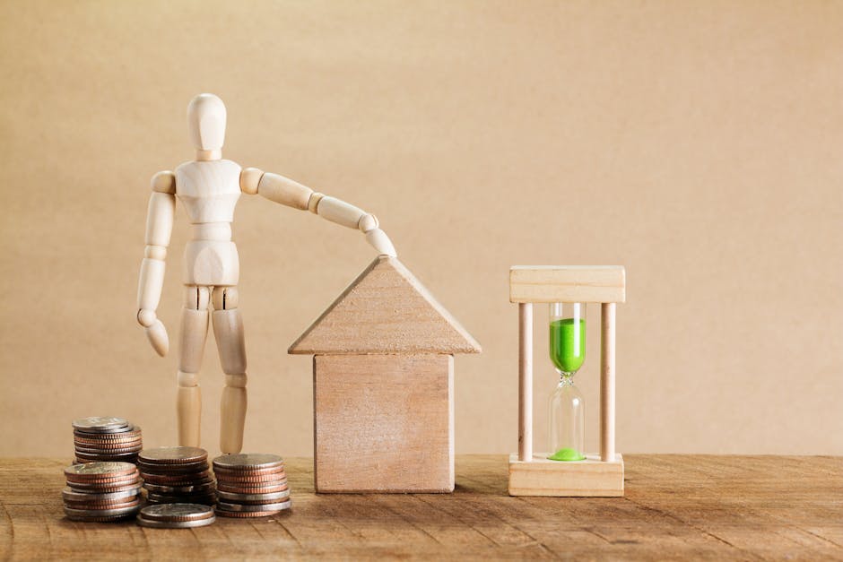 A small wooden mannequin is positioned on a light-colored wooden surface near stacks of silver coins, an arrangement of wooden and cardboard boxes, and a clear hourglass filled with green liquid, repr